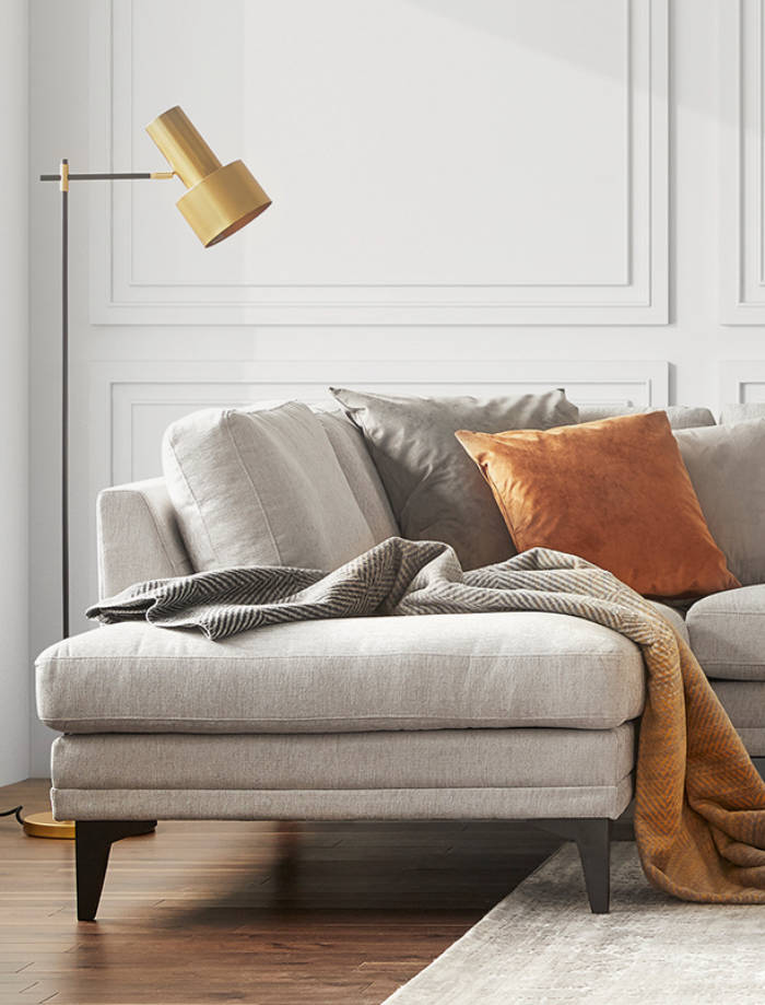 A cozy living room with a beige fabric sofa, cushions, and a designer lamp, illustrating a project for G2MC.