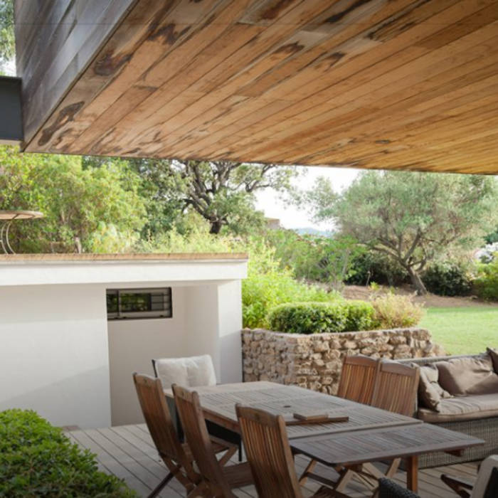 Wooden terrace with a dining table and chairs in a lush outdoor setting for Patrick Morin’s client project.