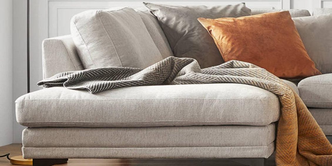 Beige sofa with cushions and a throw blanket for a cozy, elegant interior.